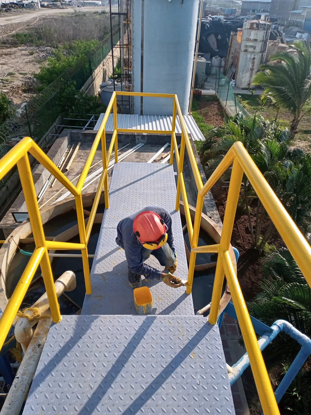 Operario pintando la pasarela con las barandas ya instaladas