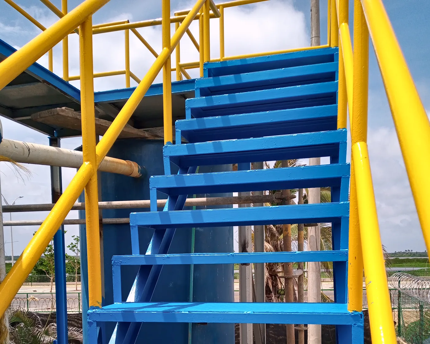 Escalera metálica azul con barandas amarillas en tubería redonda